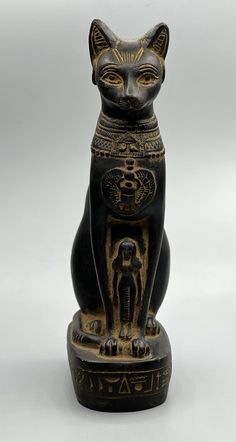 an egyptian cat figurine is shown in black and gold colors on a white background