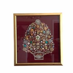 an ornately decorated christmas tree in a gold framed glass frame on a white wall