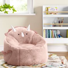 a pink bean bag chair with horns on the front and back, in a child's room