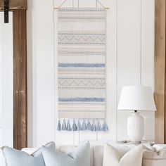 a living room with a white couch and blue throw pillows on the back of it