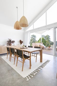 a dining room table and chairs in front of large windows