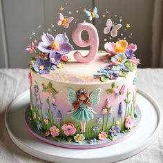 a birthday cake decorated with flowers, butterflies and a fairy number nine on it's top