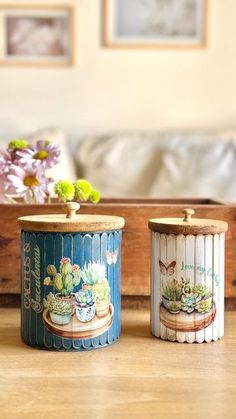 two tin canisters sitting on top of a wooden table next to a couch