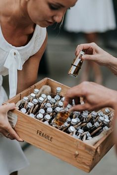 a woman holding a wooden box filled with lots of bottles