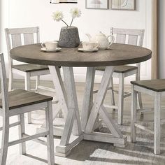 a dining room table with four chairs and a vase on top of the table in front of it