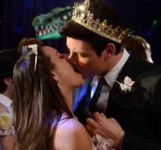 a man and woman kissing each other while wearing crowns