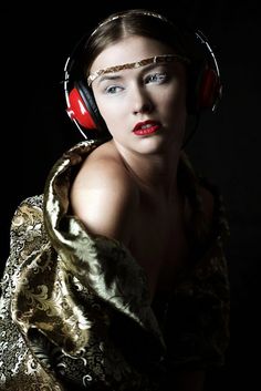 a woman with headphones on her ears and in a gold dress is posing for the camera