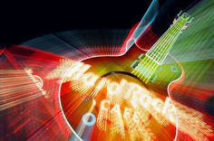 an electric guitar is shown in this artistic photo with light streaks and blurry colors