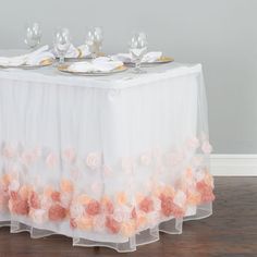 the table is set with white and pink flowers on it, along with wine glasses