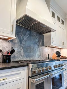 a stove top oven sitting inside of a kitchen next to white cabinets and counter tops