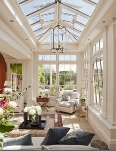 a living room filled with lots of furniture and flowers in vases on the table