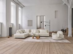 a living room with white furniture and wood floors