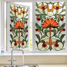 two stained glass windows with flowers on them in a kitchen window sill next to a sink