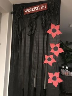 the black curtains are decorated with red and pink paper flowers that read, the upside down