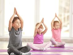 three children doing yoga on mats in a room