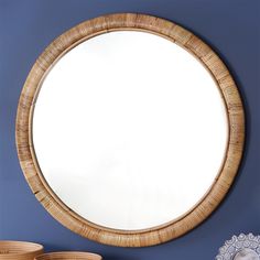 a round mirror hanging on the wall next to some bowls and baskets in front of it