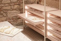 a room with some shelves and drawers on the floor in front of a stone wall