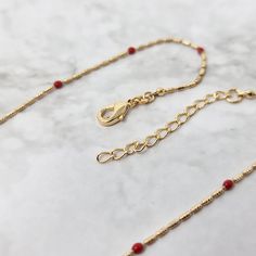 This rouge, 18k gold plated necklace features small red gemstones, set on a delicate fine chain.    Embrace the symbolism of passion and elegance with our Rouge Beaded Gold Plated Fine Necklace, a timeless piece that embodies the rich essence of love and sophistication in every delicate detail.  This jewellery arrives beautifully packaged and ready to gift. It would make a really thoughtful and meaningful birthday gift, Christmas gift, Mother's Day gift, Valentine's Day gift, anniversary gift, gift for Mum, gift for Grandma, gift for wife, gift for friend, gift for her, gift for best friend, gift for Mom, thank you gift, wedding gift, easter gift or gift for any other special occasion. JEWELLERY CARE GUIDE Our jewellery is lovingly handmade using high quality materials and semi-precious ge Red Pendant Necklace With Lobster Clasp, Elegant Red Necklace With Clavicle Chain, Elegant Red Necklace With Gold Beads, Elegant Red Clavicle Chain Necklace, 14k Gold-filled Beaded Necklaces With Gold Beads For Gifts, Elegant Red Beaded Necklace With Lobster Clasp, Elegant 14k Gold-filled Red Jewelry, Elegant Festive Necklace With Delicate Chain, Festive Elegant Necklace With Delicate Chain