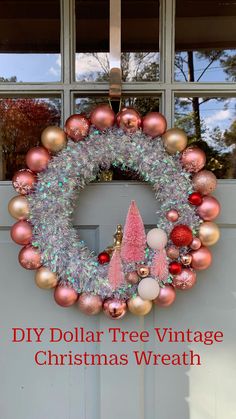 a christmas wreath hanging on the front door with ornaments all around it and a pink cone