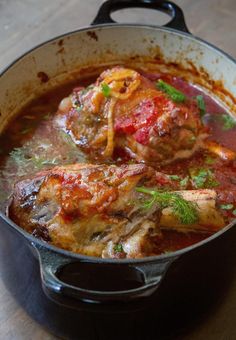 a pot filled with meat and sauce on top of a wooden table