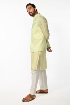 Mint green bam silk kurta with mirror embroidery. Comes with ivory cotton silk pyjama pant and a bundi with welt pockets.
Components: 3
Pattern: Hand embroidered
Type Of Work: Mirror
Neckline: Mandarin collar
Sleeve Type: Bundi : Sleeveless, Kurta : Full
Fabric: Kurta and Bundi : Bam silk, Pant : Cotton silk
Color: Green
Other Details: 
Side slits on kurta
Closure : Front buttons
Occasion: Mehendi and Haldi, Sangeet - Aza Fashions Collar Kurta, Sleeveless Kurta, Silk Pajama Pants, Mirror Embroidery, Silk Pant, Green Mirror, Silk Kurta, Nehru Jackets, Pajama Pant