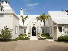 a white house with blue shutters and palm trees