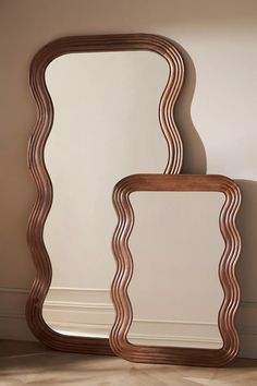 two mirrors sitting next to each other on top of a wooden floor near a wall