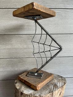 a spider web lamp on top of a tree stump in front of a wooden wall