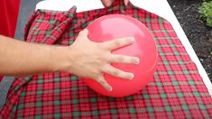 a person holding a red frisbee on top of a tarp covered table