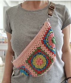 a woman is holding a crocheted purse in her hands and wearing a gray shirt