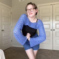 a woman wearing glasses and a blue sweater is posing for the camera with her hands on her hips