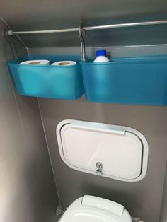 a toilet with two blue bins above it