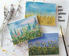 three cards with flowers painted on them sitting next to paintbrushes and watercolors