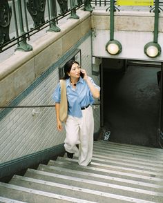 a woman walking up some stairs talking on her cell phone