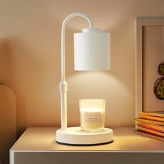 a white table lamp sitting on top of a desk next to a candle