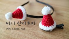 two crocheted santa hats sitting on top of a wooden table