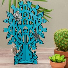 a blue decorative stand next to a cactus and potted plant on a wooden table