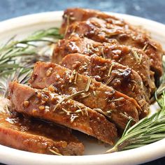 some meat on a plate with rosemary sprigs