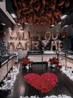 a room filled with lots of red flowers and balloons that say i love you marry