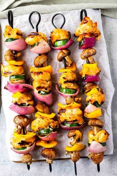 several skewers filled with different types of food on top of a sheet of paper