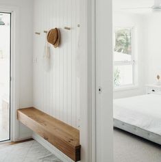 a bedroom with white walls and wooden bench