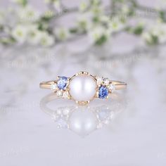 an image of a ring with pearls and blue sapphires on the side, sitting on a table