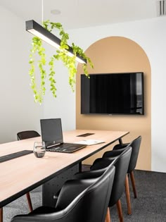 a table with chairs and a laptop on it in front of a flat screen tv