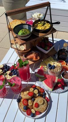 a table topped with plates and bowls filled with food next to watermelon slices