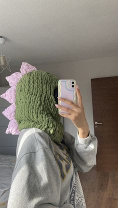 a woman taking a selfie with her cell phone wearing a crocheted hat