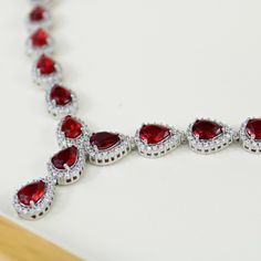 WHITE GOLD FINISH Red Ruby Pear Cut Cluster Created Diamond Necklace | Wedding, Engagement, Celebration, Birthday, Gift This beautiful created diamond necklace is made as the perfect gift for a loved one! Either for yourself, a friend, or a dear one, this necklace is made with love, compassion and care, just for you! The ruby is a lustrous, deep red stone that has accrued special and symbolic meaning through time. Through the ages, the ruby has represented nobility, purity, and passion.  Rubies, the birthstone of July, are considered the king of gems and represent love, health and wisdom. It was believed wearing a fine red Ruby bestowed good fortune on its owner. A Ruby is the most valuable gemstone and its value increases based on its colour and quality. The Ruby represents love, passion, Formal Ruby Necklace For Valentine's Day, Classic Red Necklaces For Anniversary, Red Formal Necklace For Valentine's Day, Elegant Necklaces For Valentine's Day Celebration, Red Formal Necklaces For Valentine's Day, Red Cubic Zirconia Bridal Necklace For Wedding, Elegant Red Bridal Necklace For Anniversary, Valentine's Day Formal Teardrop Necklace, Red Cubic Zirconia Necklace For Anniversary