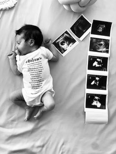 a baby laying on top of a bed next to pictures