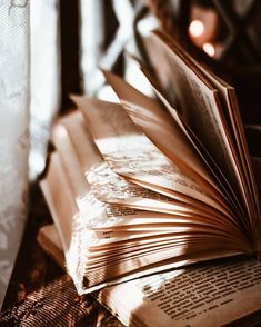 an open book sitting on top of a table next to a glass vase and candle