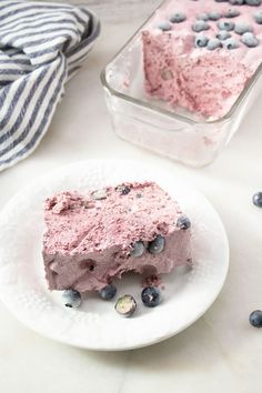 a piece of cake on a plate with blueberries and ice cream in the background