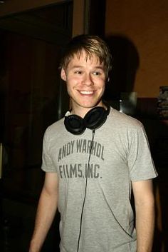 a young man wearing headphones standing in front of a door